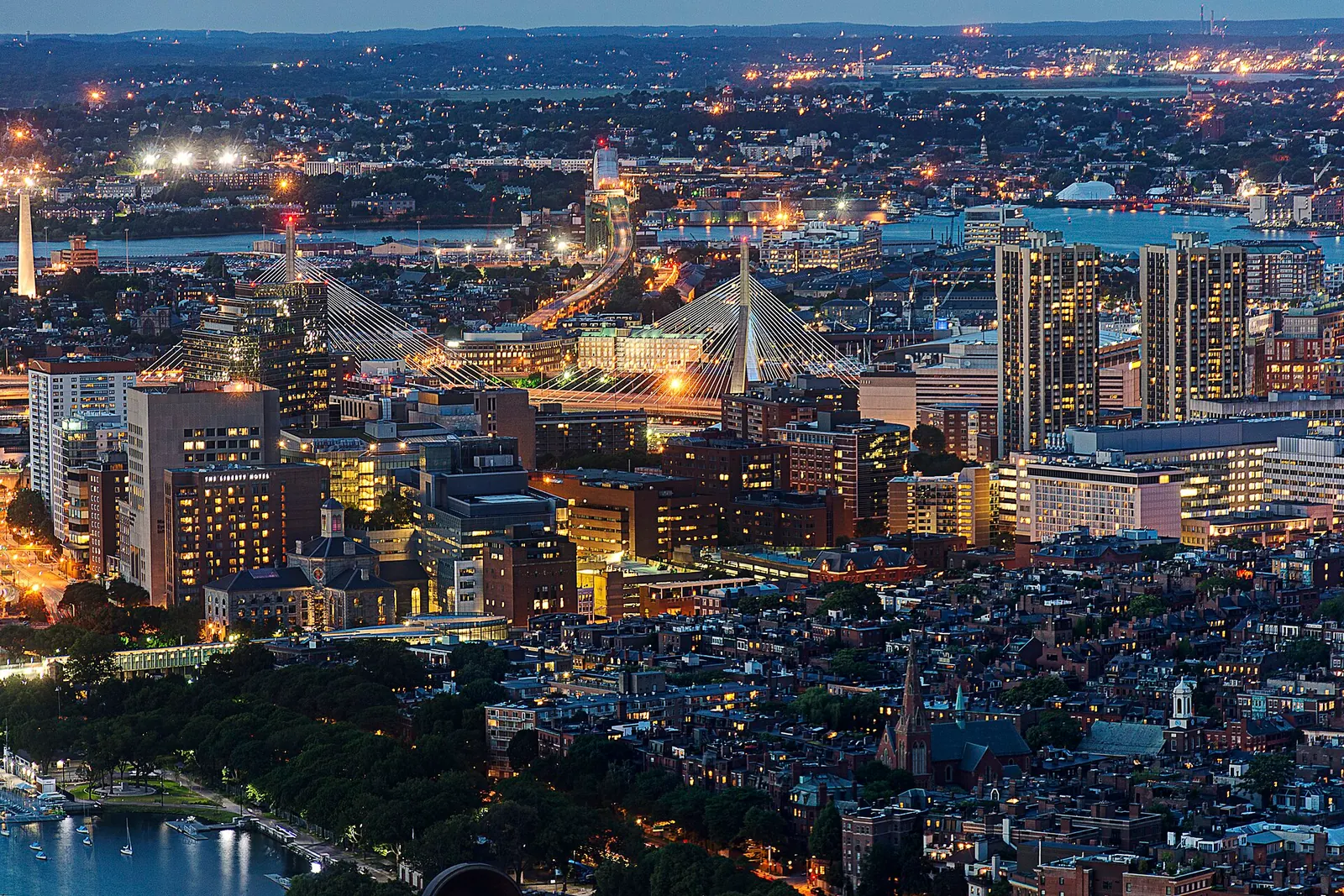 Boston’s buildings and bridges lit up at dusk, seen from the Prudential Tower.