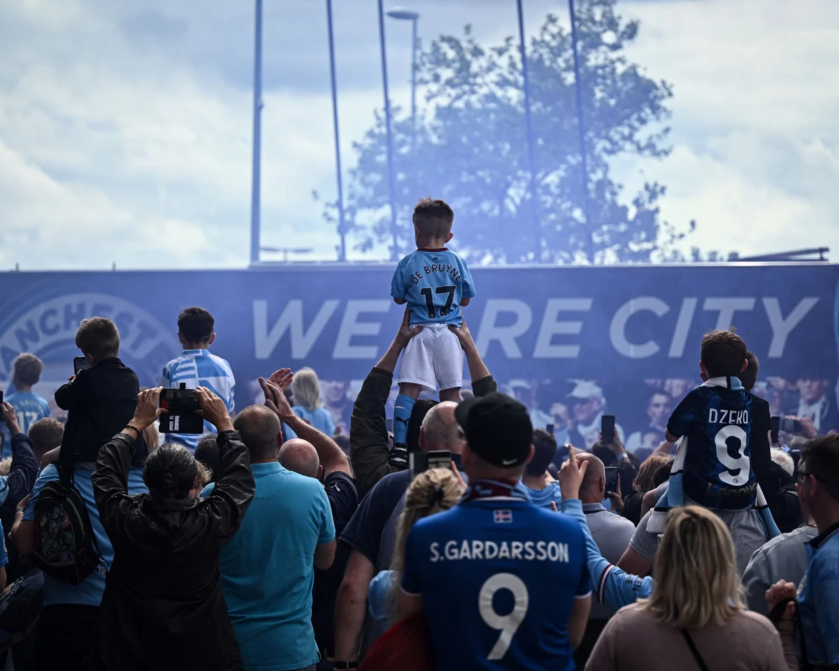 Manchester City supporters, including a child on a supporter’s shoulders.