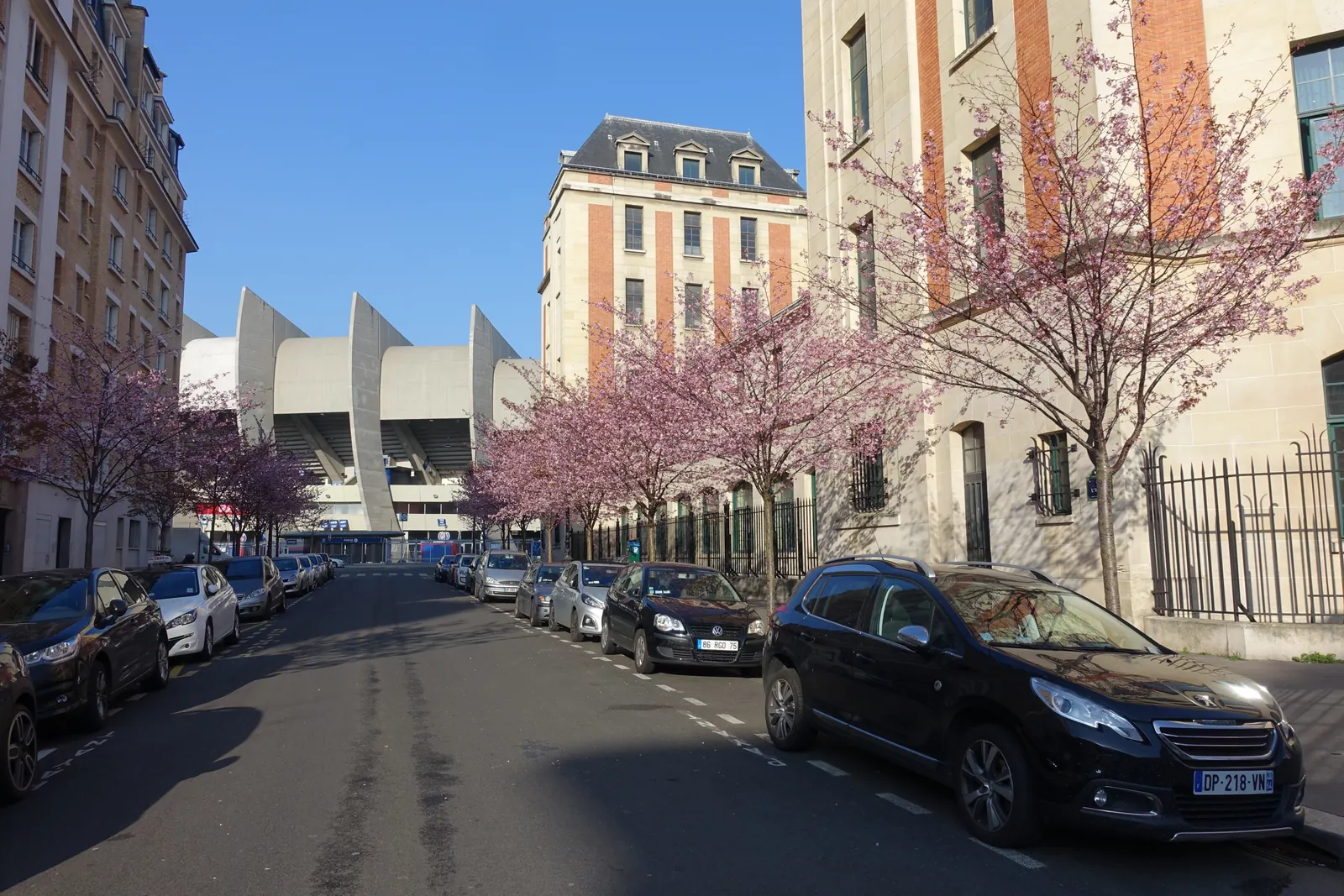 The Parc des Princes at the end of a Paris street lined with flowering trees.